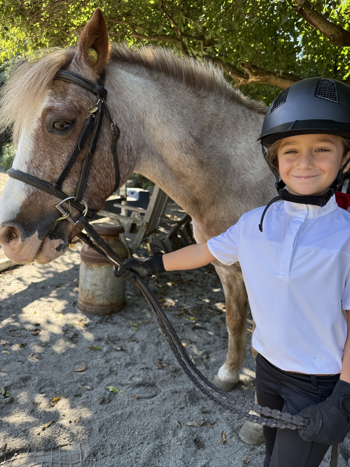 Smiling young rider standing beside a pony at Winding Hill Stables