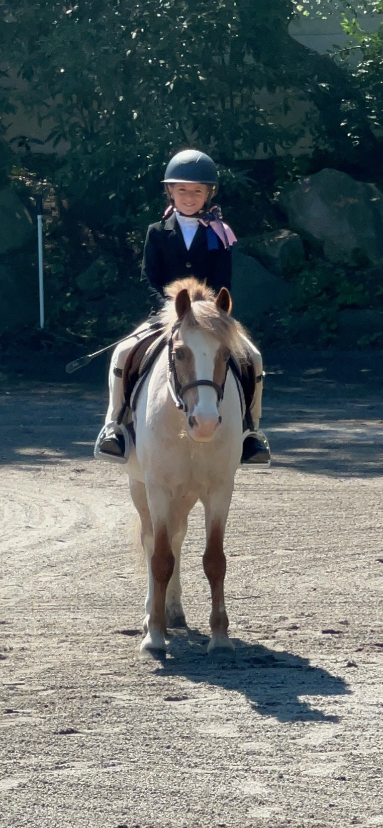 Smiling young rider in show attire sitting on a pony at Winding Hill